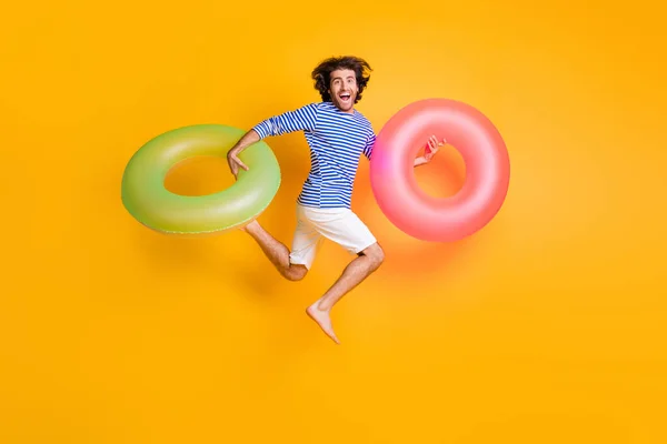 Foto de comprimento total de cara louco salto executar espera vida bóia desgaste azul branco shorts isolado sobre cor amarela fundo — Fotografia de Stock