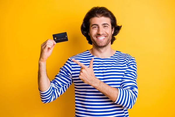 Foto van positieve Midden-Oosten man wijzen vinger credit card dragen blauw wit jurk geïsoleerd op fel gele kleur achtergrond — Stockfoto