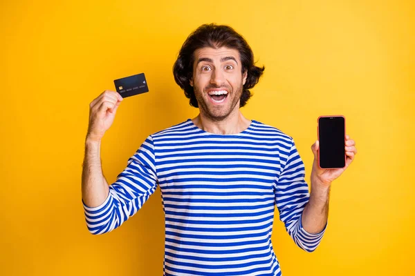 Foto van gek verbaasd Midden-Oosten man houden smartphone credit card slijtage jurk geïsoleerd over gele kleur achtergrond — Stockfoto