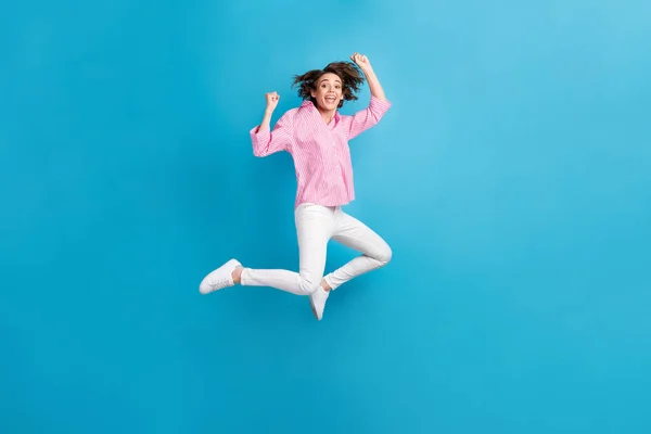 Foto in voller Größe von ekstatischen Mädchen springen heben Fäuste tragen formale Kleidung Turnschuhe isoliert über blauer Farbe Hintergrund — Stockfoto