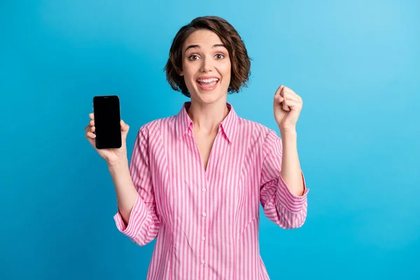 Foto de louco encantado senhora segurar smartphone levantar punhos usar camisa listrada isolada sobre fundo de cor azul — Fotografia de Stock