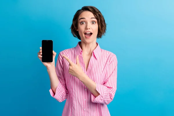 Foto van verbaasd dame punt index vinger mobiele telefoon dragen witte formalwear shirt geïsoleerd over blauwe kleur achtergrond — Stockfoto