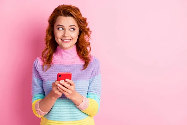 Portrait photo de femme tenant le téléphone dans les deux mains regardant l'espace vide isolé sur fond rose pastel — Photo