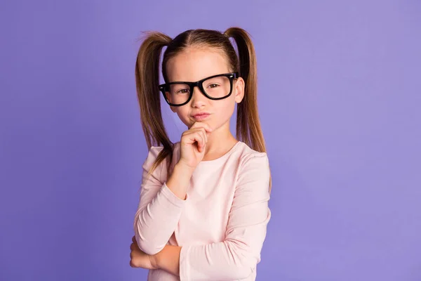 Foto de inteligente encantadora niña seria usar gafas sostener la barbilla de la mano aislado en el fondo de color violeta — Foto de Stock