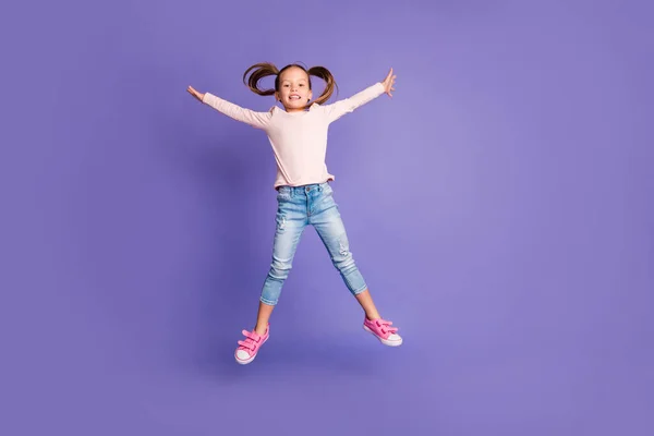 Foto de tamaño completo de niña bastante alegre saltar a la forma de estrella usar jeans aislados en el fondo de color violeta —  Fotos de Stock