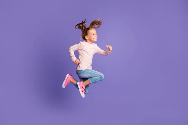 Full size profile side photo of brown haired tails little girl wear jeans sweater jump run isolated on purple color background — Stock Photo, Image