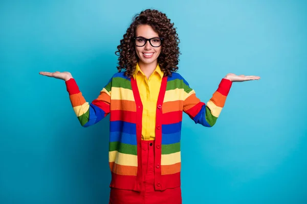 Retrato de conteúdo muito alegre menina de cabelos ondulados segurando nas palmas das mãos demonstrando espaço de cópia isolado no fundo de cor azul brilhante — Fotografia de Stock