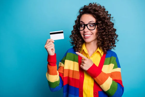 Genç kıvırcık saçlı kızın fotoğrafı işaret parmağı, kredi kartı mutlu gülümseme, mavi arka planda izole edilmiş alışveriş satın al. — Stok fotoğraf