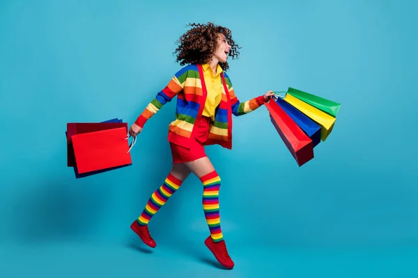 Perfil de corpo inteiro foto lateral da jovem mulher usar saia executar compras levar sacos isolados sobre fundo de cor azul — Fotografia de Stock