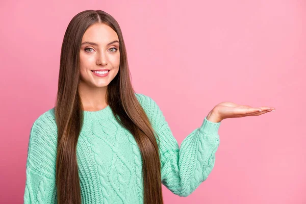 Portret van vriendelijke jonge dame toon arm houden product slijtage turquoise trui geïsoleerd op roze kleur achtergrond — Stockfoto