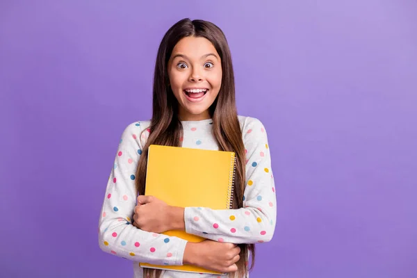 Foto retrato de la colegiala sorprendida feliz abrazando libro amarillo preparándose para la lección sonriendo aislado sobre fondo de color púrpura brillante — Foto de Stock