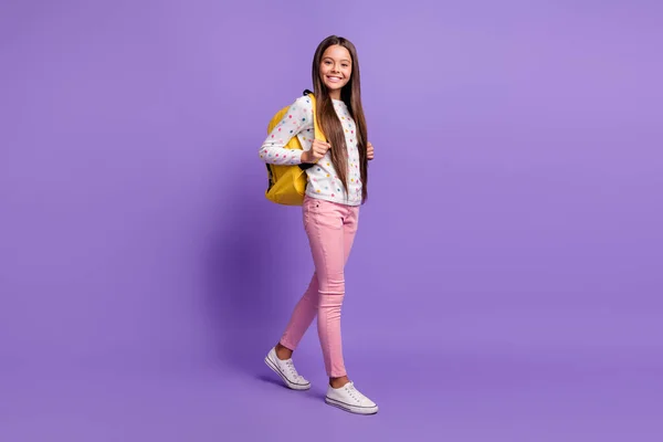 Tamanho do corpo de comprimento total foto de menina pré-adolescente com cabelos longos carregando mochila amarela sorrindo feliz isolado no fundo violeta brilhante — Fotografia de Stock