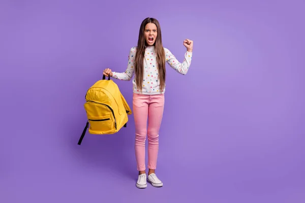 Tamanho total do corpo foto de menina irritada irritada mantendo mochila amarela gritando mostrando punho isolado no fundo roxo vibrante — Fotografia de Stock