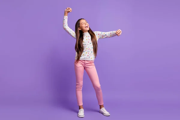 Foto ukuran tubuh penuh dari gadis kecil menari bermain-main mengenakan sepatu olahraga celana jumper terisolasi pada latar belakang warna ungu cerah — Stok Foto
