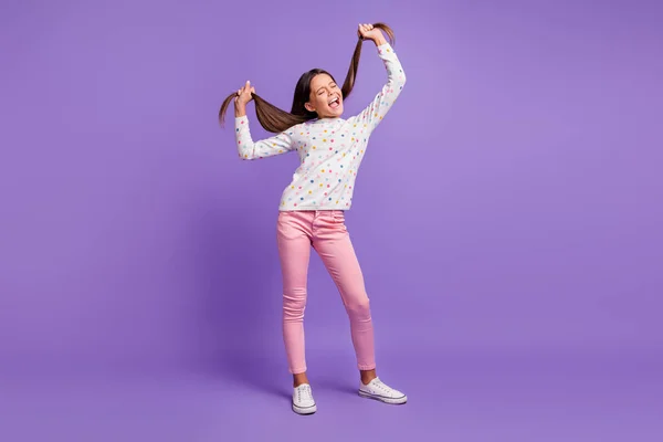 Foto de tamaño corporal de larga duración de una niña pequeña cantando en voz alta manteniendo las colas de pelo largas ojos cerrados aislados en el vibrante fondo de color púrpura — Foto de Stock