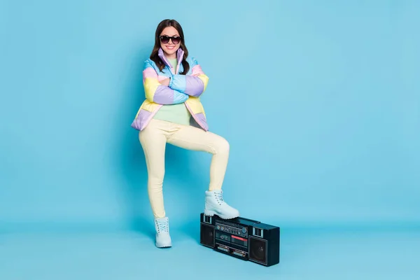 Fotoportrett av en kul jente med foldede armer som setter fot på en boombox isolert på pastellblå bakgrunn – stockfoto