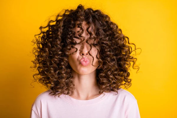 Kopfschuss des Mädchens mit lockiger Frisur trägt T-Shirt senden Luftkuss geschmückten Lippen isoliert auf lebendigen gelben Farbhintergrund — Stockfoto
