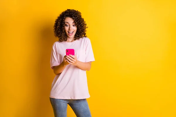 Foto-Porträt von lockigem Mädchen mit Smartphone im Internet surfen isoliert auf leuchtend gelbem Hintergrund — Stockfoto