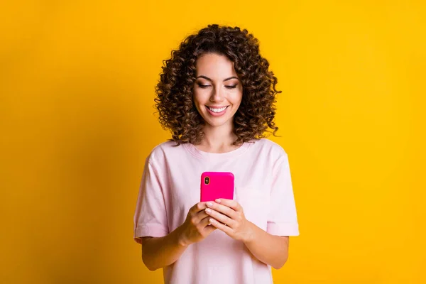 Foto porträtt av kvinna leende hålla telefonen i två händer isolerade på levande gul färgad bakgrund — Stockfoto