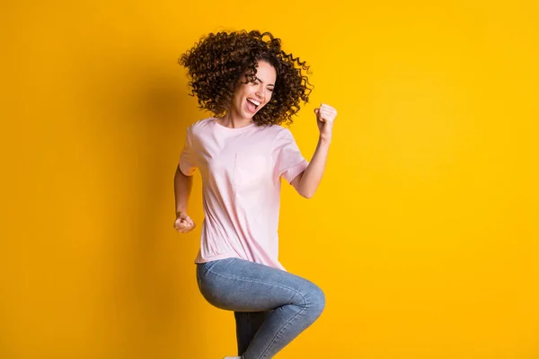 Foto retrato de una niña celebrando de pie sobre una pierna aislada sobre un fondo de color amarillo vivo — Foto de Stock