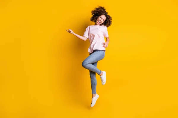 Fényképezés portré teljes test kilátás lány jumping up játszik képzeletbeli gitár elszigetelt élénk sárga színű háttér — Stock Fotó
