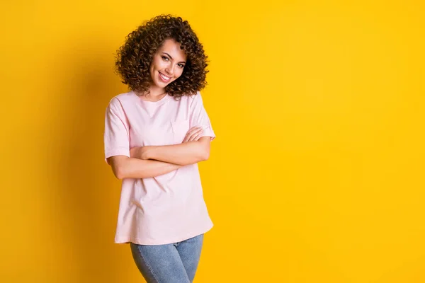 Φωτογραφία του νεαρού σγουρά καστανά μαλλιά κορίτσι αυτοπεποίθηση χαμόγελο ελκυστική σταυρωμένα χέρια απομονώνονται σε κίτρινο χρώμα φόντο — Φωτογραφία Αρχείου