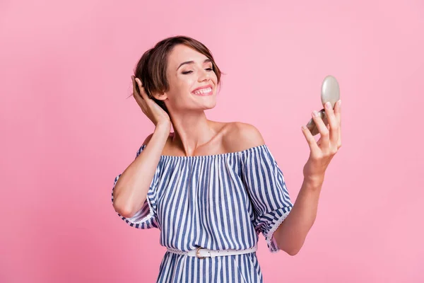 Foto retrato de una joven bonita mirando el espejo tocando el peinado bob sonriendo alegremente aislado sobre fondo de color rosa pastel —  Fotos de Stock