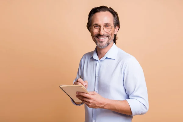 面白い起業家の男の写真ノートを保持する書き込み眼鏡シャツ孤立ベージュ色の背景 — ストック写真