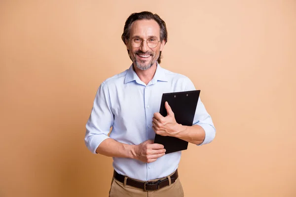 Foto di fiducioso ragazzo di successo tenere appunti indossare occhiali camicia isolato colore beige sfondo — Foto Stock