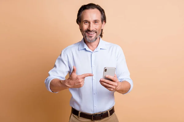 Sakallı adamın fotoğrafı akıllı telefonu işaret parmağına bak kamera gömleği giy izole edilmiş bej arka plan — Stok fotoğraf