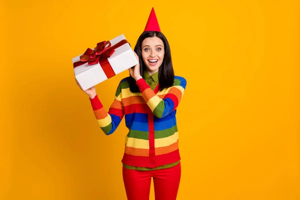 Foto de alegre sonrisa feliz niña desgaste partido sombrero celebrar caja de regalo sorprendido aislado sobre fondo de color amarillo —  Fotos de Stock