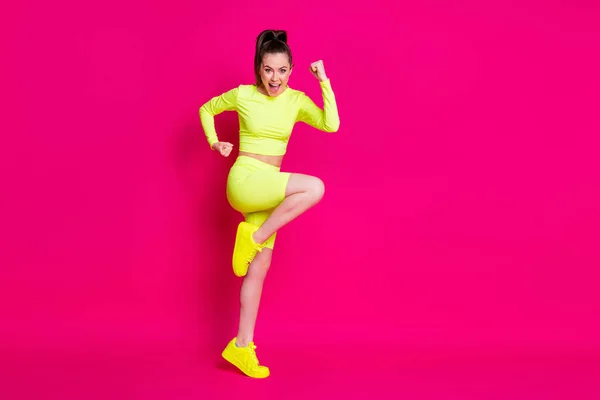 Фотографія профілю повного розміру дивовижної молодої леді стоїть кулаками вгору крикливе плаття спортивний костюм кросівки ізольовані на фоні рожевого кольору — стокове фото