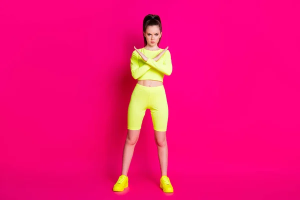 Ciddi çapraz kollu sporcu kadının tam boy fotoğrafı açık pembe arka planda izole edilmiş sarı kısa giysiyi gösteriyor. — Stok fotoğraf