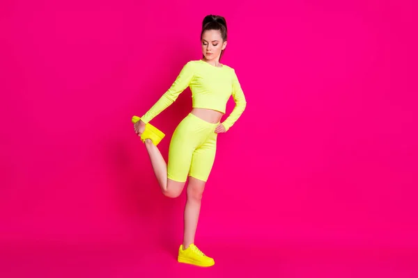 Foto de cuerpo entero de la deportista estirar pierna usar zapatillas de deporte amarillas pantalones cortos aislados en el fondo de color rosa brillante —  Fotos de Stock