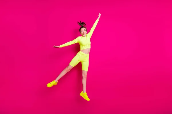 Foto de tamaño corporal de longitud completa de saltar alta joven deportista que usa zapatillas de deporte amarillas aisladas en el vibrante fondo de color rosa —  Fotos de Stock