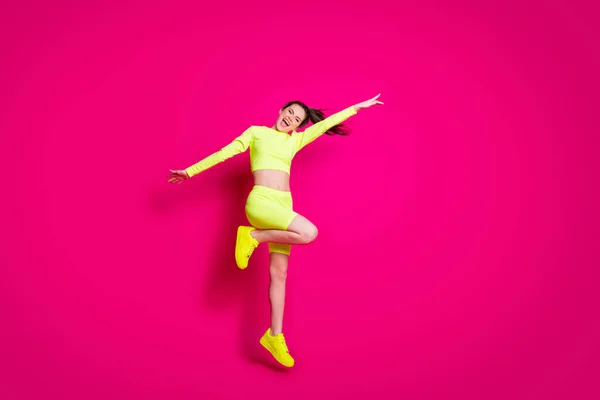 Foto de tamaño completo del cuerpo de la deportista saltando riendo alegremente usando ropa deportiva con estilo aislado en el fondo de color rosa brillante —  Fotos de Stock