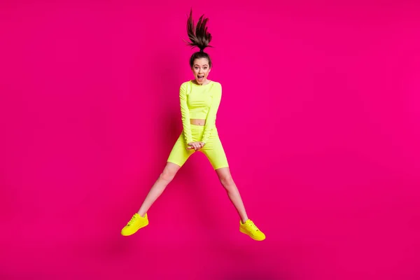 Longitud completa tamaño del cuerpo foto de la deportista saltando riendo con ropa deportiva cola de caballo aislado sobre fondo de color rosa brillante — Foto de Stock