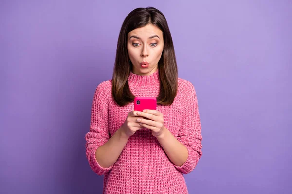 Фотопортрет здивованої дівчини, що переглядає мобільний телефон в Інтернеті та ізольований на яскравому фіолетовому кольоровому фоні — стокове фото