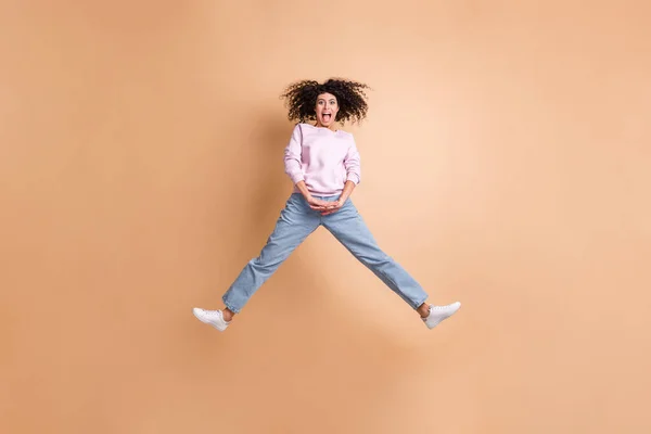 Фотографія активної привабливої людини, що стрибає відкритим ротом, отримує задоволення ізольовано на коричневому кольоровому фоні — стокове фото