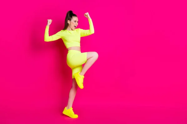 Full size profiel foto van verbaasd jonge dame staan vuisten omhoog schreeuwen kijken lege ruimte jurk sport pak geïsoleerd op roze kleur achtergrond — Stockfoto