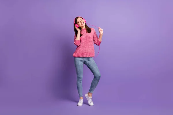 全长体形照片，年轻女子穿着耳机在派对上跳舞，在充满活力的紫色背景下唱着歌 — 图库照片