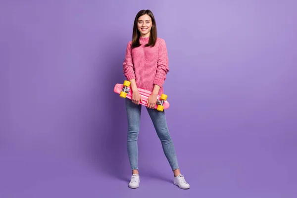 Longitud completa tamaño del cuerpo foto de estudiante femenina sonriendo mantener monopatín rosa aislado sobre fondo de color púrpura vivo —  Fotos de Stock