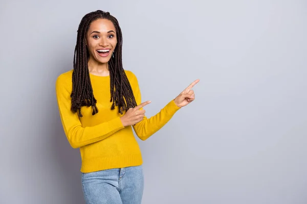 Foto av ung upphetsad svart kvinna glad leende indikerar fingrar tomt utrymme promo rekommenderar besluta isolerad över grå färg bakgrund — Stockfoto