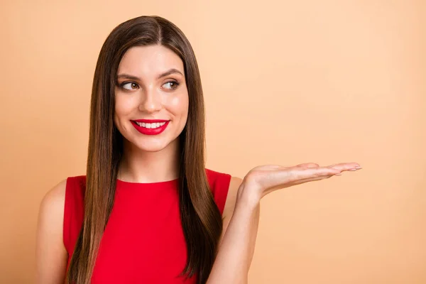 Foto van vrolijke vrolijke vrouw look houden hand lege ruimte demonstreren object geïsoleerd op beige kleur achtergrond — Stockfoto