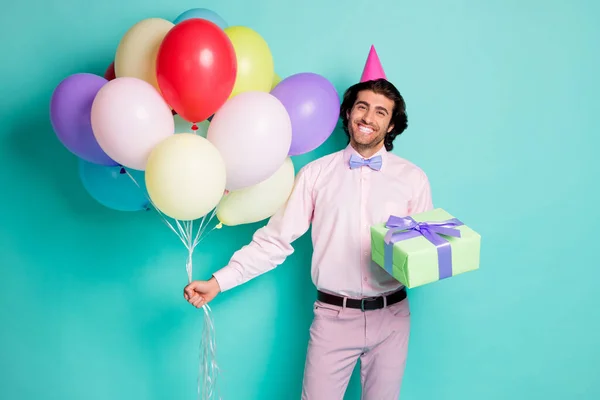 Retrato de chico sonriente mantenga globos de colores presente caja vestida de cono formalwear aislado sobre fondo de color turquesa — Foto de Stock