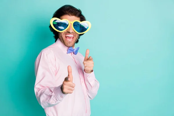 Foto de chico guapo tienen estado de ánimo loco vestido formalwear gafas de sol en forma de corazón que apuntan aislado sobre fondo de color turquesa —  Fotos de Stock