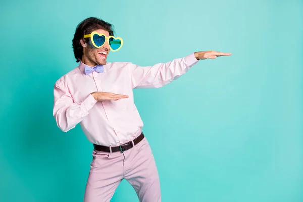 Foto de hombre bailando funky vestido arco gafas de sol en forma de corazón se ven espacio vacío aislado sobre fondo de color turquesa —  Fotos de Stock