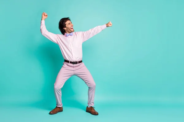 Foto de perfil de alegre morena pelo rizado clubber hombre llevar camisa rosa baile estiramiento puños lado mirando vacío espacio aislado verde azulado color fondo —  Fotos de Stock