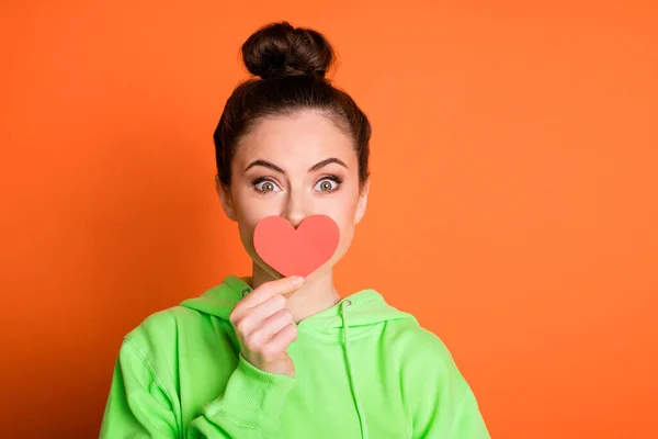 Foto de flerte bonito jovem senhora vestida camisola verde papel vermelho tampa do coração boca isolado cor laranja brilhante fundo — Fotografia de Stock