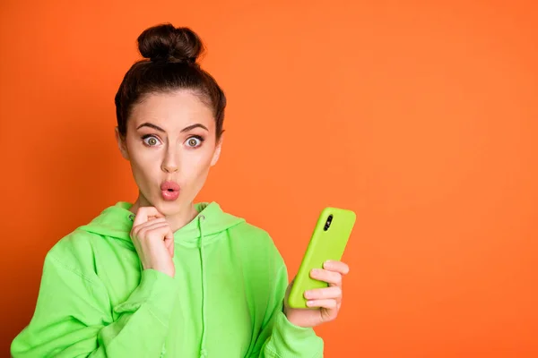 Portrait photo de femme choquée tenant le téléphone dans une main isolée sur fond orange vif avec un espace vide — Photo